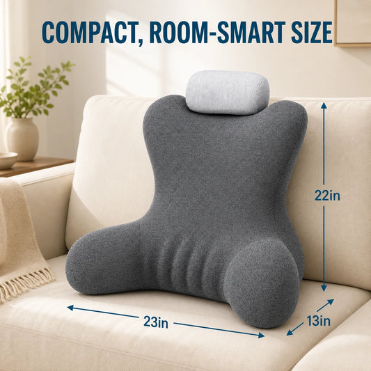 A dark gray contoured lumbar pillow with a matching light gray headrest cushion, displayed on a beige sofa. Blue dimension lines and text overlay indicate its size as 23 inches wide, 22 inches tall, and 13 inches deep, with the headline 'COMPACT, ROOM-SMART SIZE' at the top.
